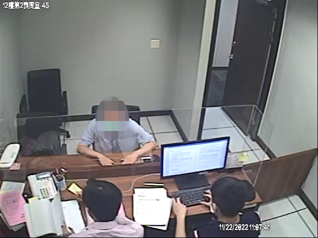義務人至新北分署報告後，行政執行官(背對鏡頭左)作勢填寫留置通知單。